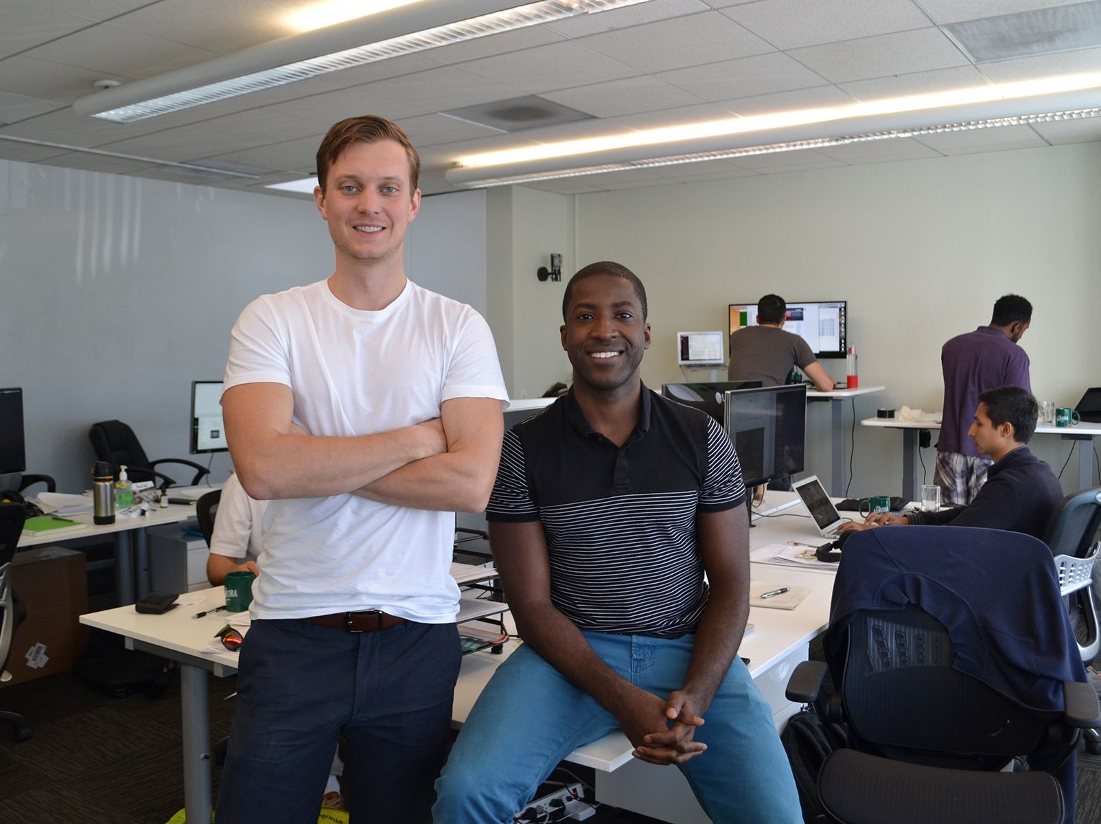 Christopher Hopper and Samuel Adeyemo with colleagues working at computers in an early Aurora Solar office