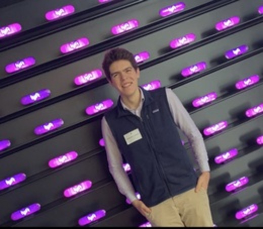 Christopher Lambert standing in front of a wall of purple-lit hardware at a security event