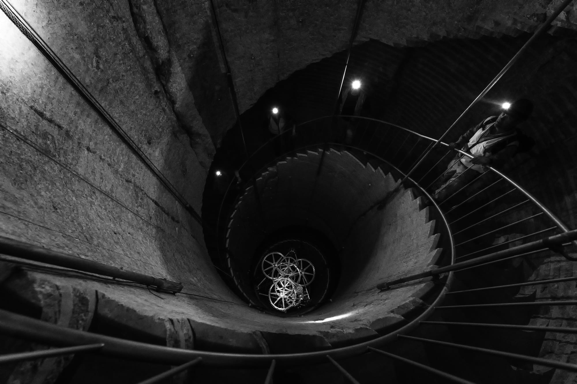 A person on a spiral staircase above clockwork inside the Long Now clock project in Texas