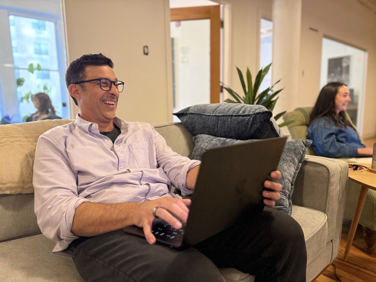 Christopher O’Donnell laughing with a laptop on an office couch