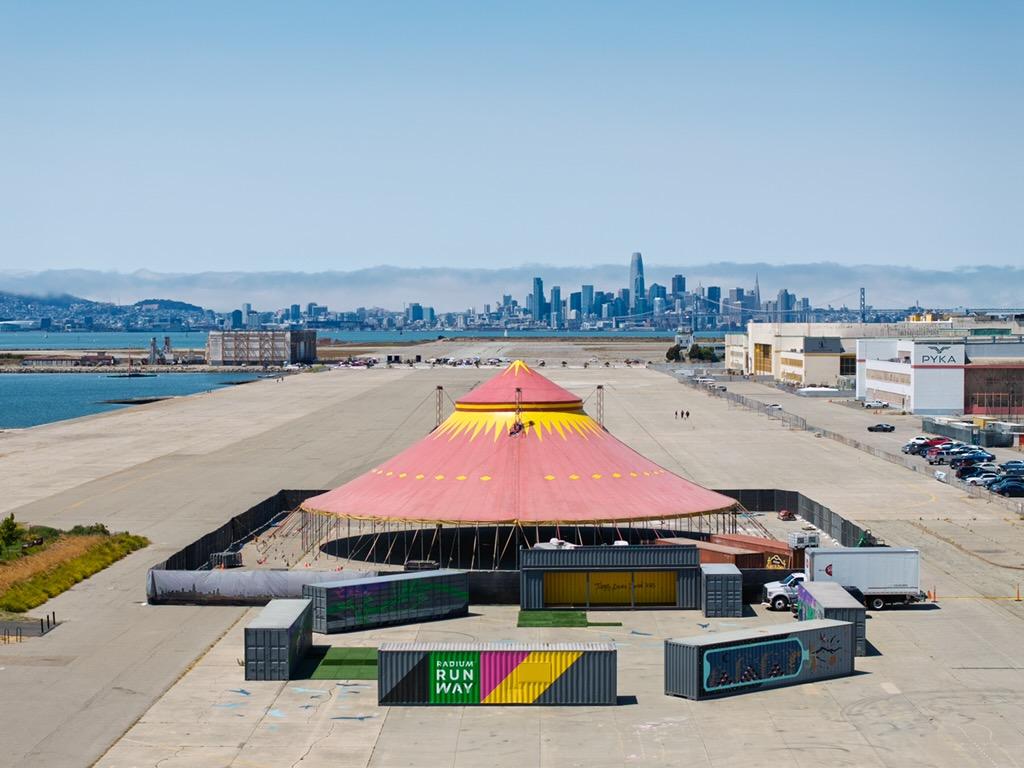 The colorful big top at Radium Runway on Alameda’s waterfront, with San Francisco in the distance
