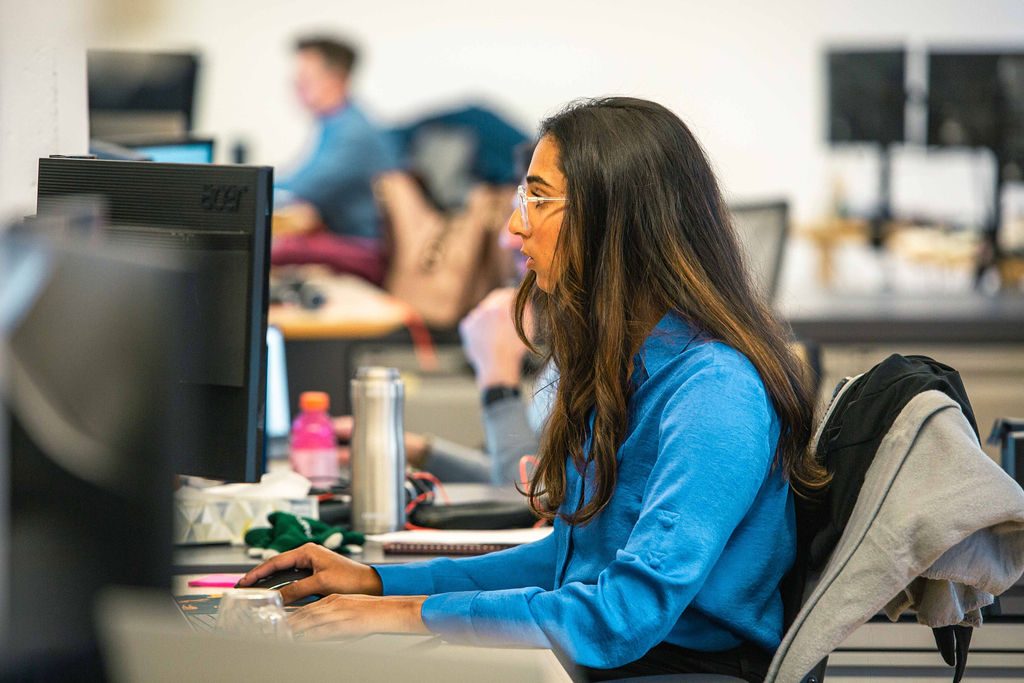 A colleague working at a desktop computer in an office photograph published by TopBloc