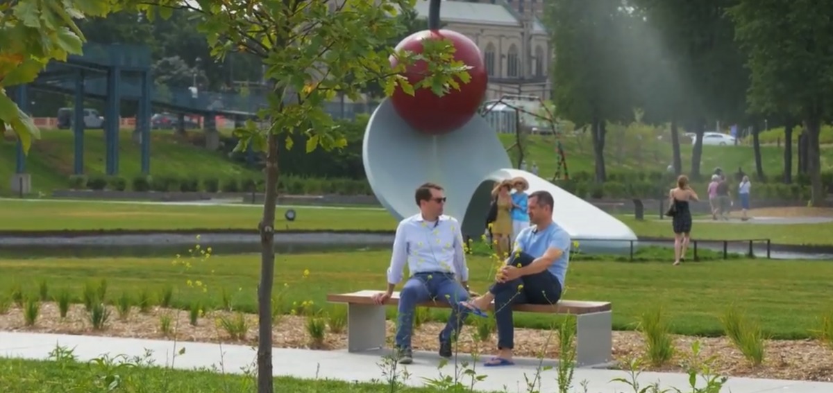 Christopher Smith speaking with an interviewer on a bench in the Minneapolis Sculpture Garden