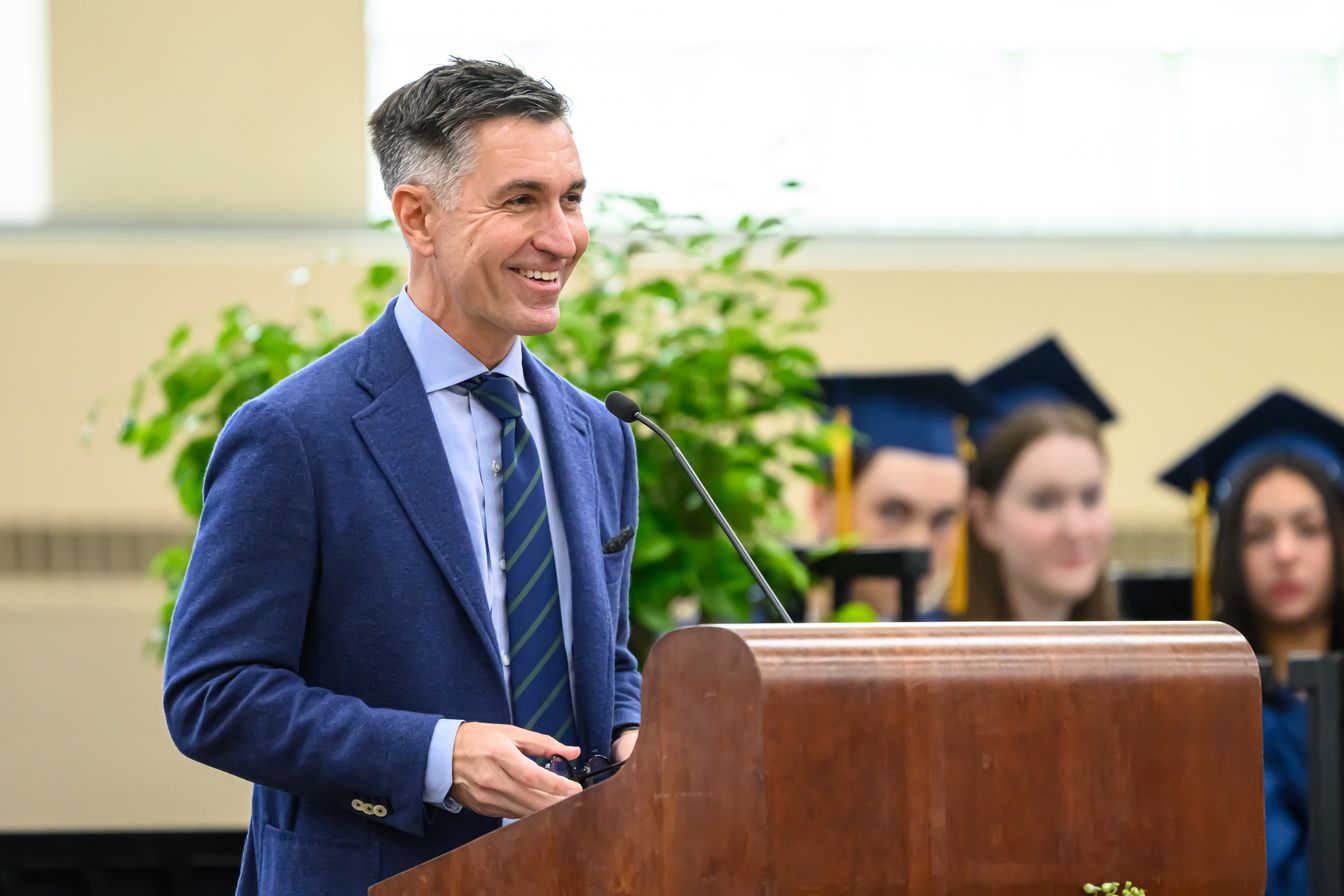Chuck Brizius smiling as he speaks at a lectern during BB&N’s 2024 graduation