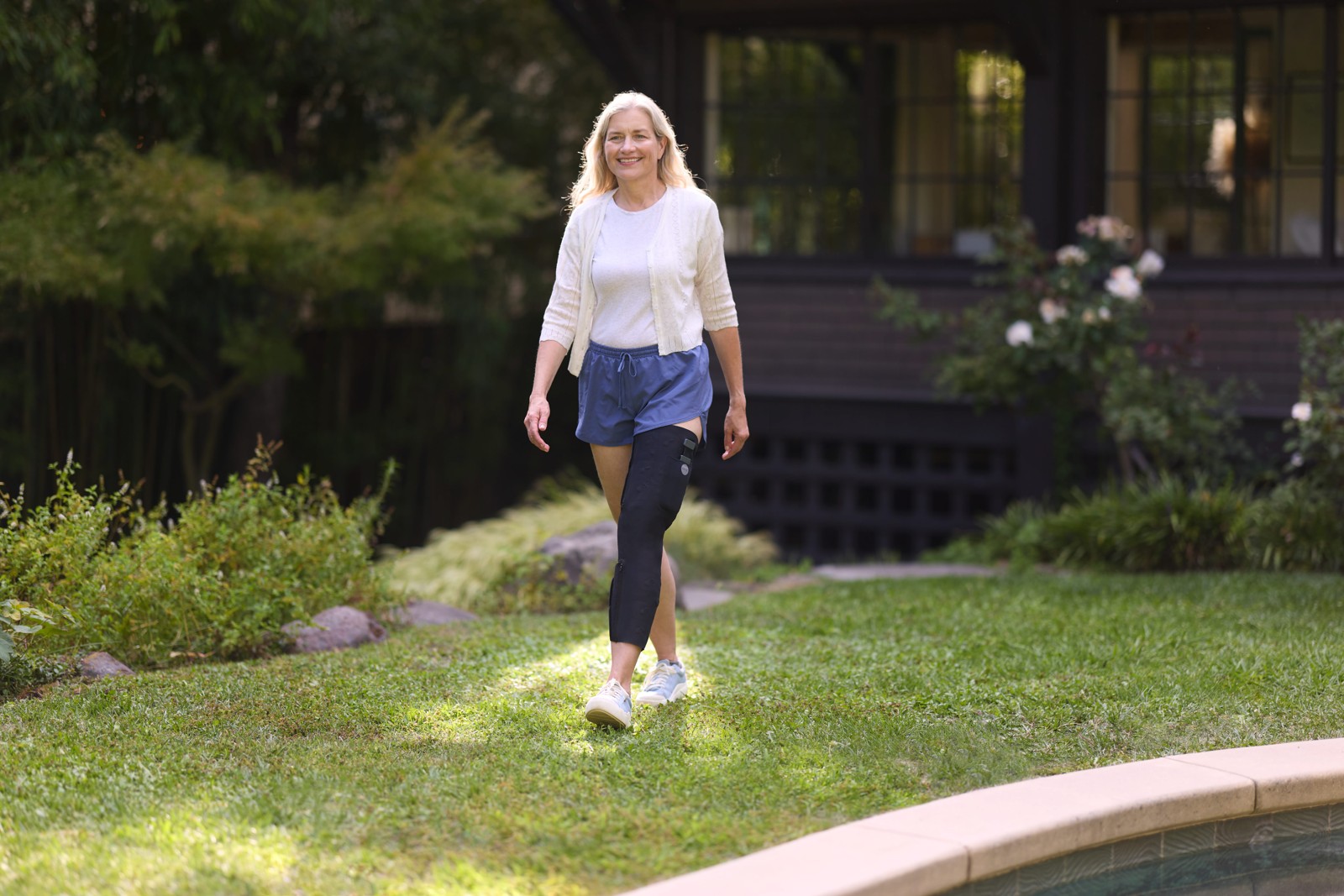 A woman wearing a CIONIC leg sleeve walks along a garden path