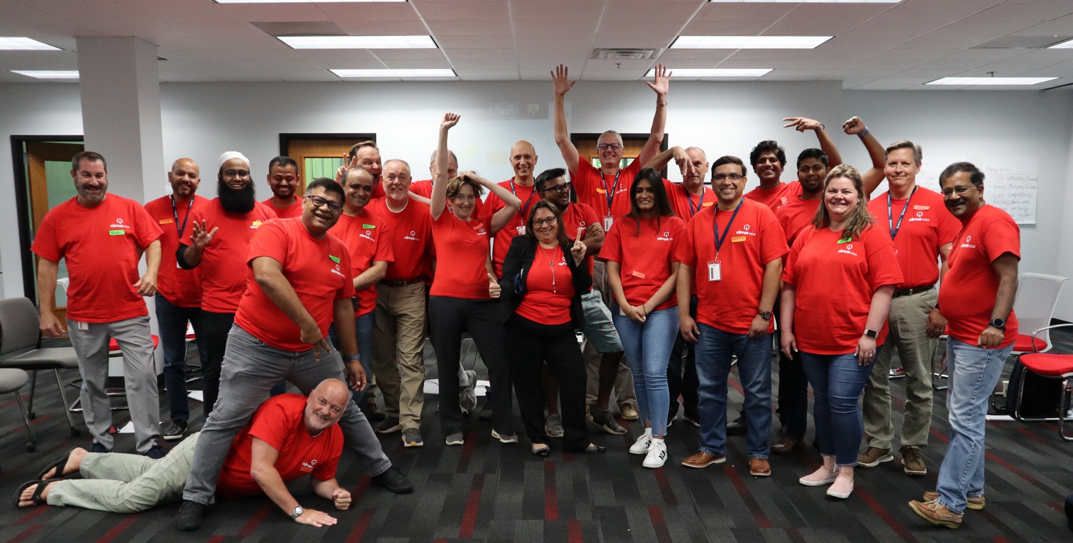 CirrusLabs colleagues in matching red shirts pose together in a meeting room