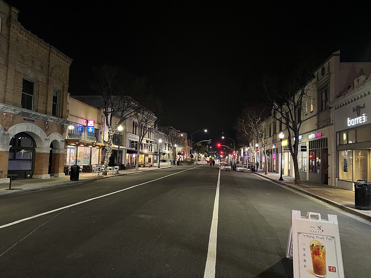 B Street at night, with illuminated storefronts, outdoor tables and an open roadway