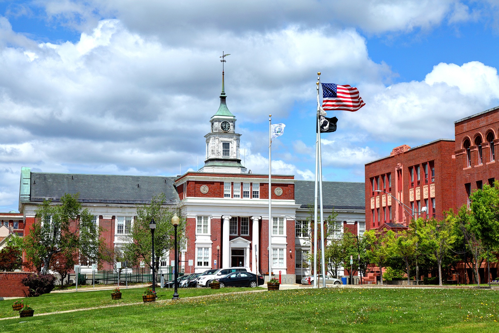 Somerville City Hall beneath a cloud-filled sky, with flags above the lawn