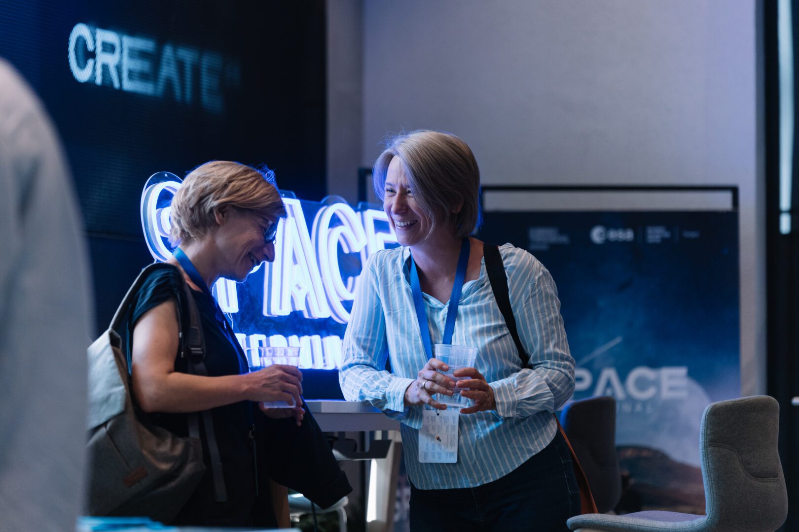 Two attendees talking beside illuminated Space Terminal lettering at an event
