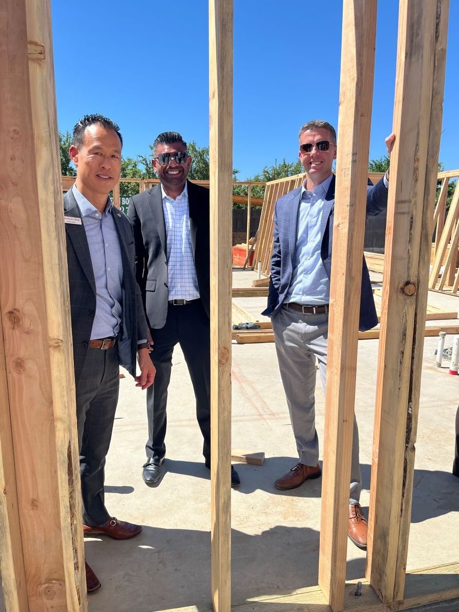 Mechanics Bank representatives standing among timber framing at the Planada housing construction site