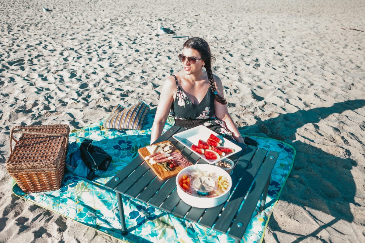 Claire Bahn sitting beside a picnic table on the beach