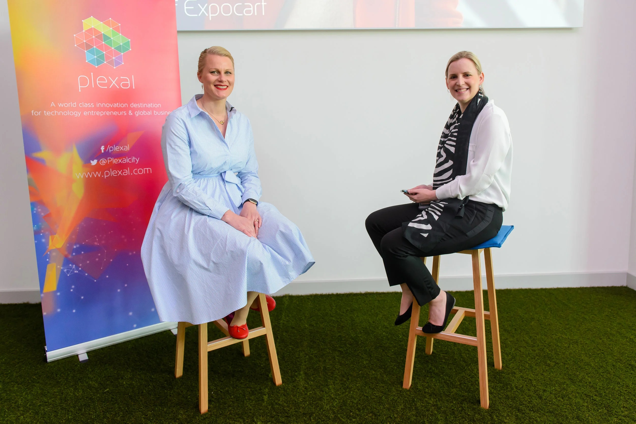 Claire Cockerton, seated on the left, at a Plexal launch interview beside a colourful Plexal banner