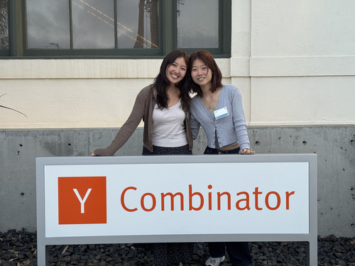Claire Mao and Lucy Cai standing together behind a Y Combinator sign