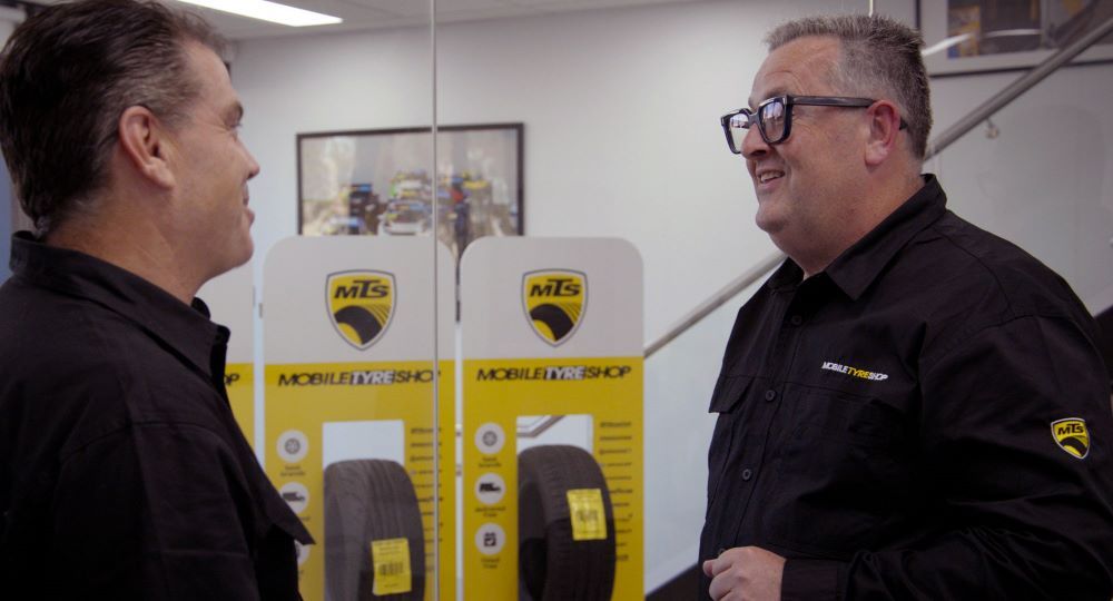 Two Mobile Tyre Shop colleagues talking beside tyre displays