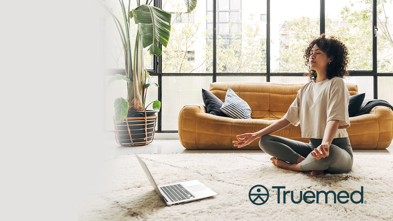 A woman meditating beside a laptop in Clarity's Truemed partnership artwork
