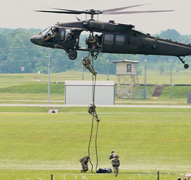 Military personnel training beneath a helicopter at Fort Campbell