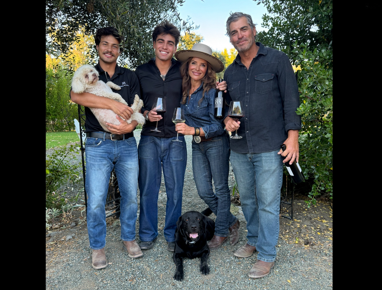 Claudia Castillo Ross with the Ross family, wine bottles and two dogs at the ranch
