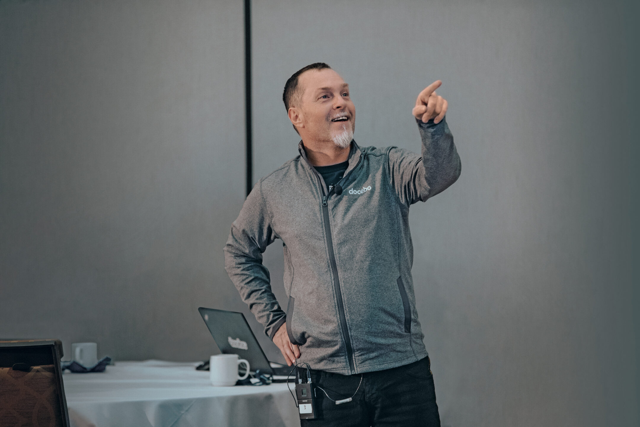 Claudio Erba gesturing while speaking beside a laptop, wearing a Docebo jacket