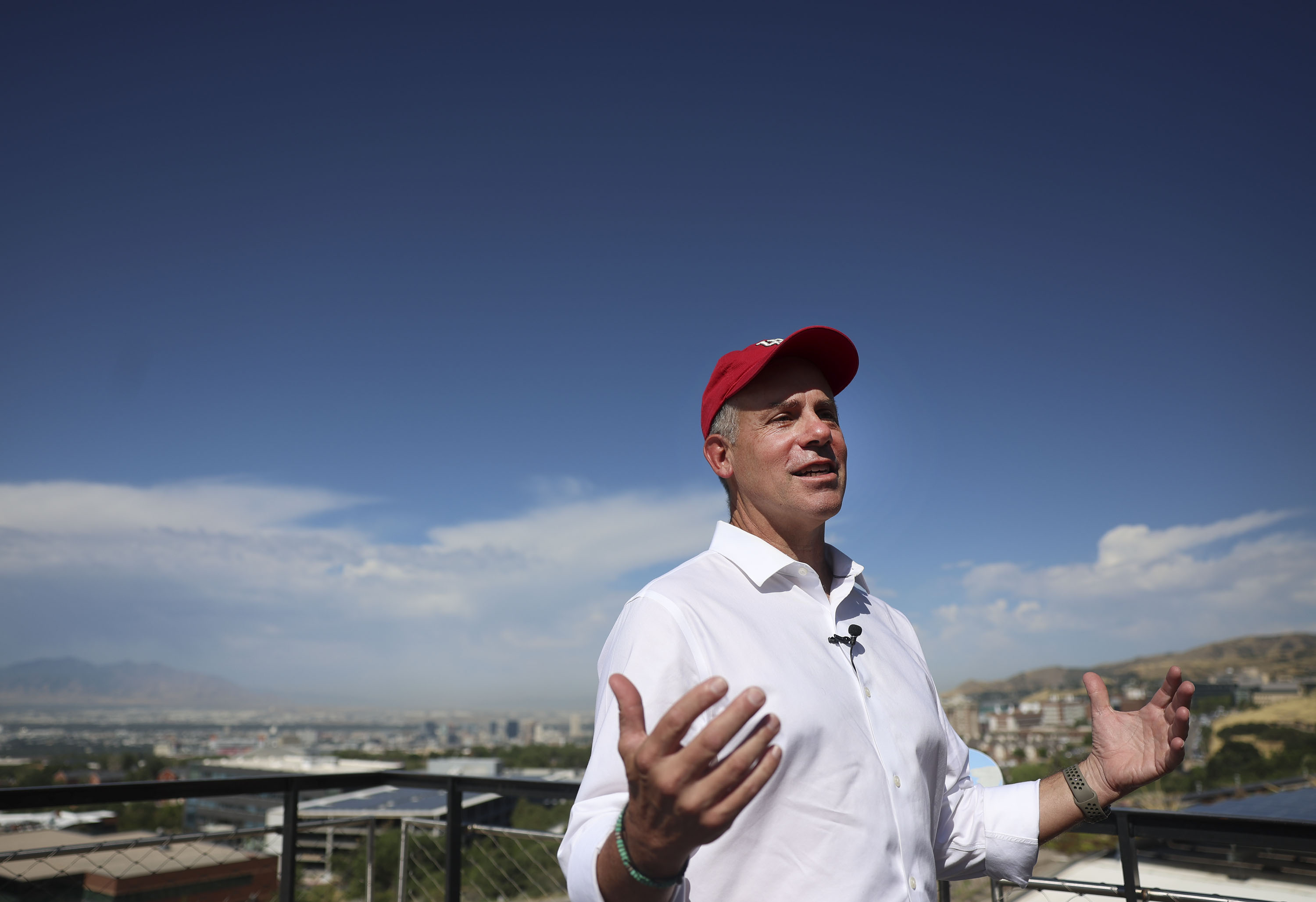 Clay Wilkes addresses the climate center announcement outdoors, with Salt Lake City in the distance.
