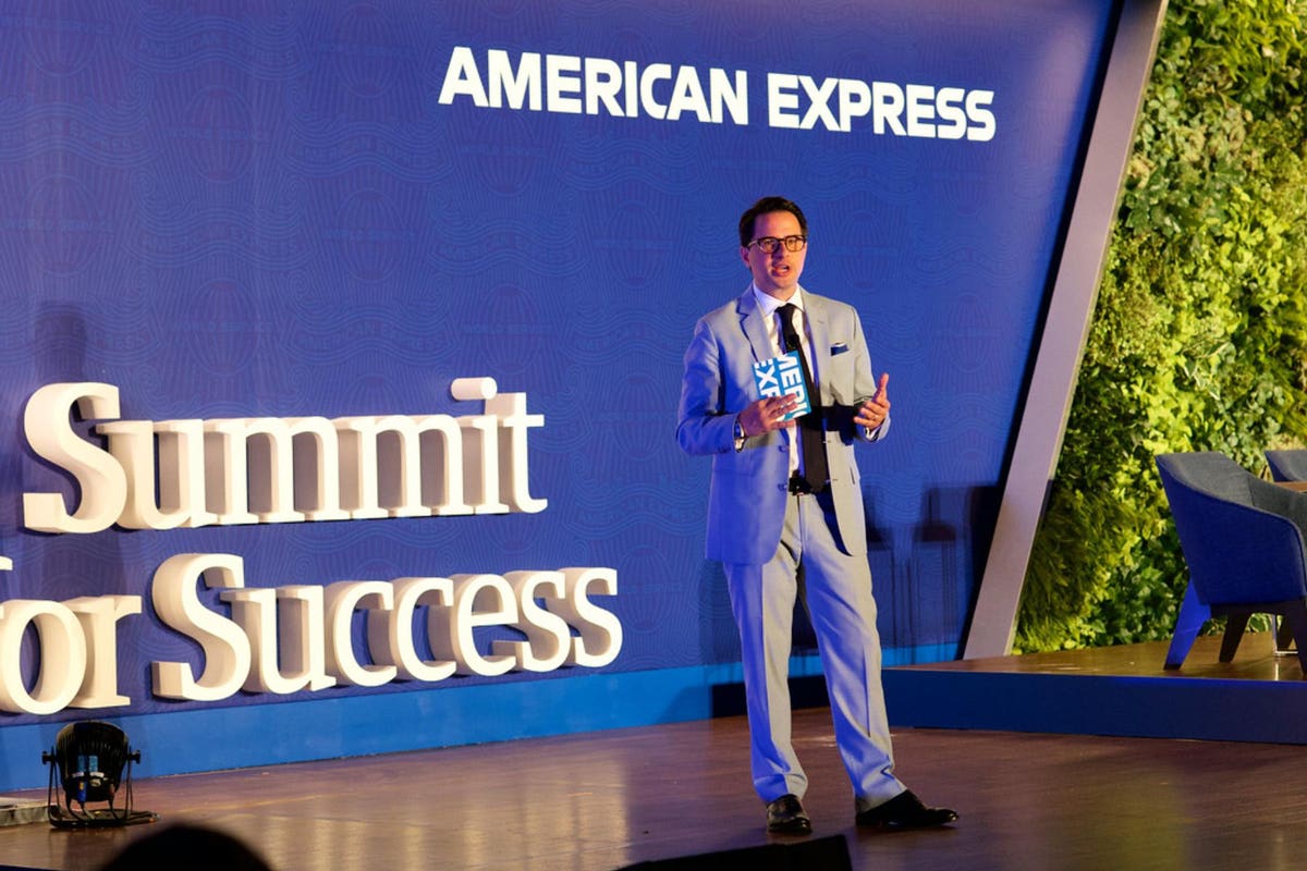 Clayton Ruebensaal speaking onstage at an American Express Summit for Success