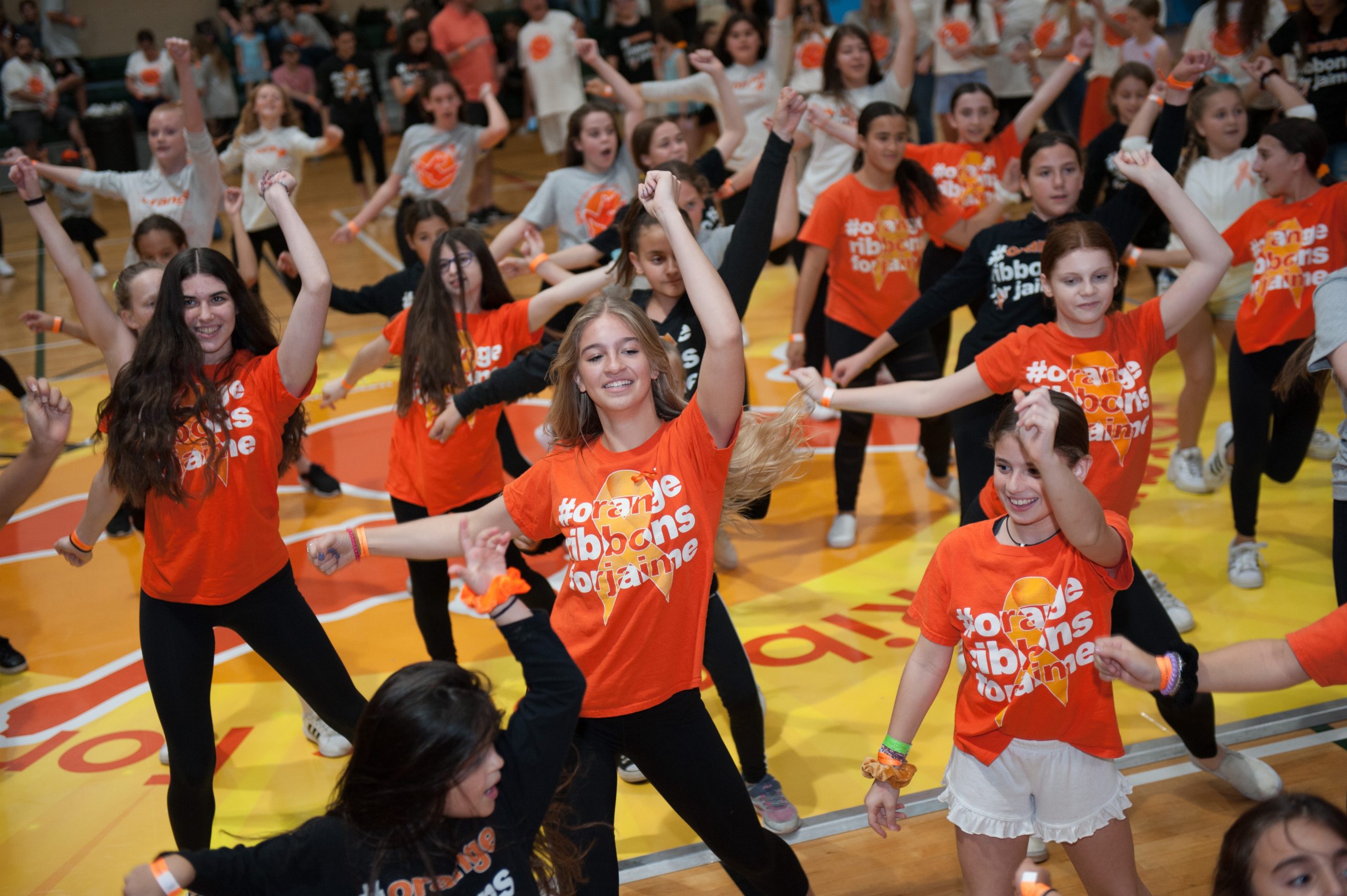Young dancers in orange shirts take part in an Orange Ribbons for Jaime dance-a-thon
