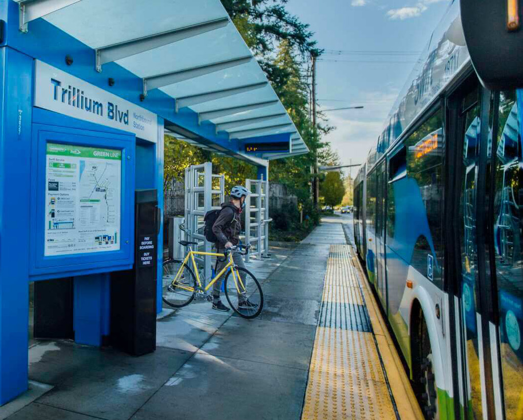 A passenger with a bicycle beside a Community Transit bus at Trillium Boulevard station