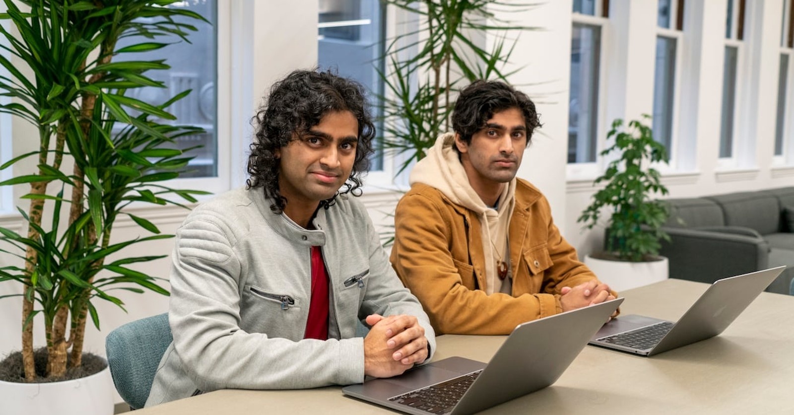 Cloaked co-founders Arjun and Abhijay Bhatnagar seated at a table with laptops