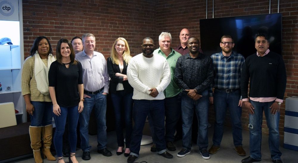 Cloud Technology Partners team members standing together in a brick-walled office