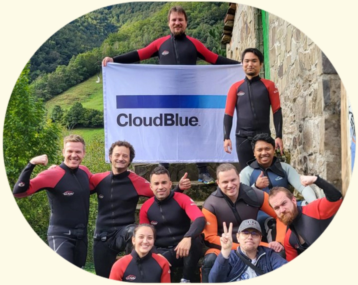 CloudBlue team members in wetsuits holding a company flag outdoors