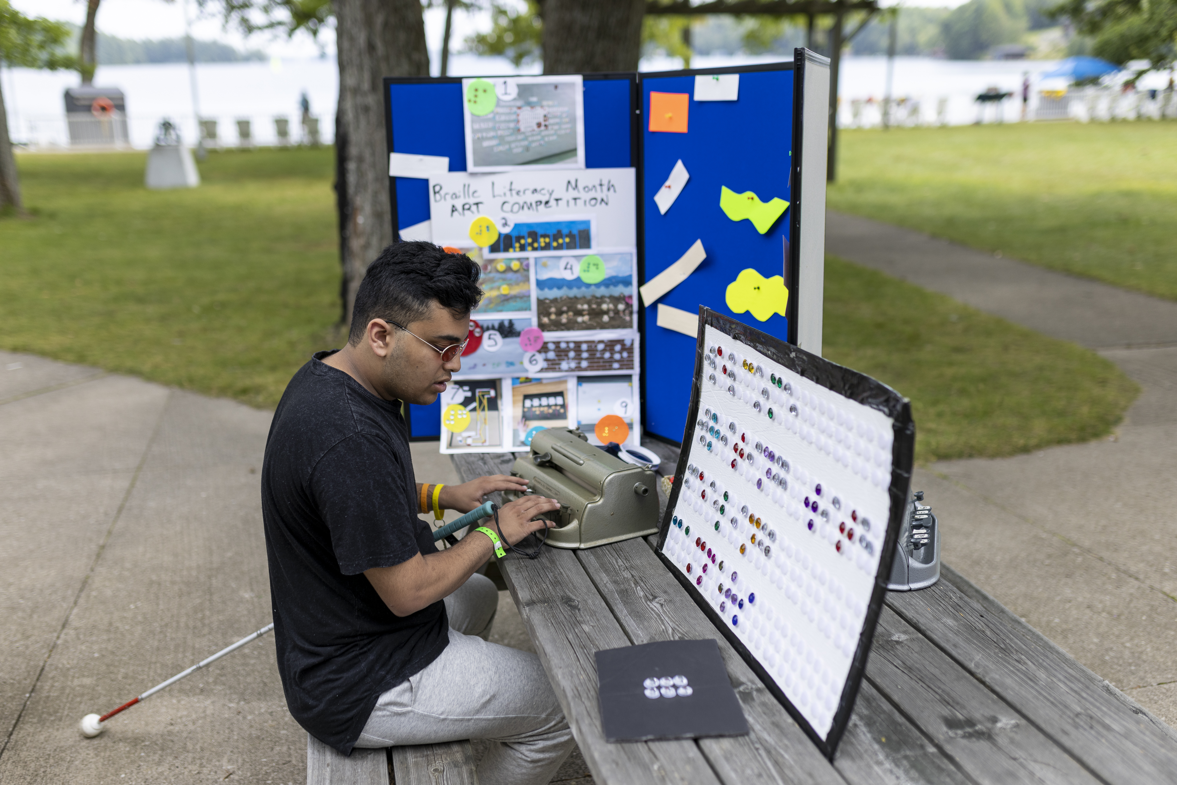 A young person uses a braille typewriter at a picnic table during a CNIB Lake Joe program.