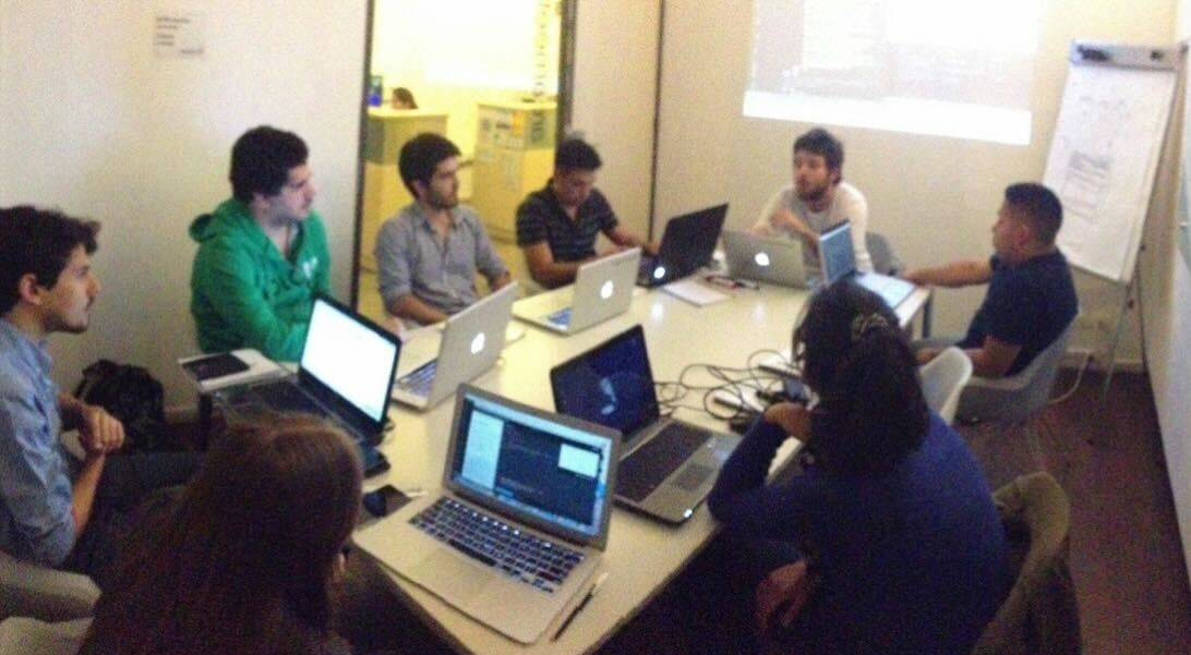 An early Coderhouse classroom with learners and laptops around a shared table