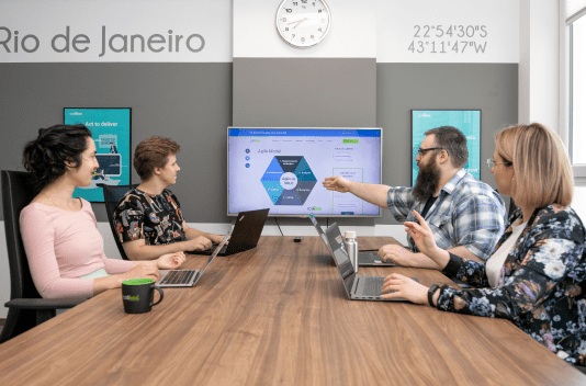CodiLime colleagues discussing a presentation around a meeting table