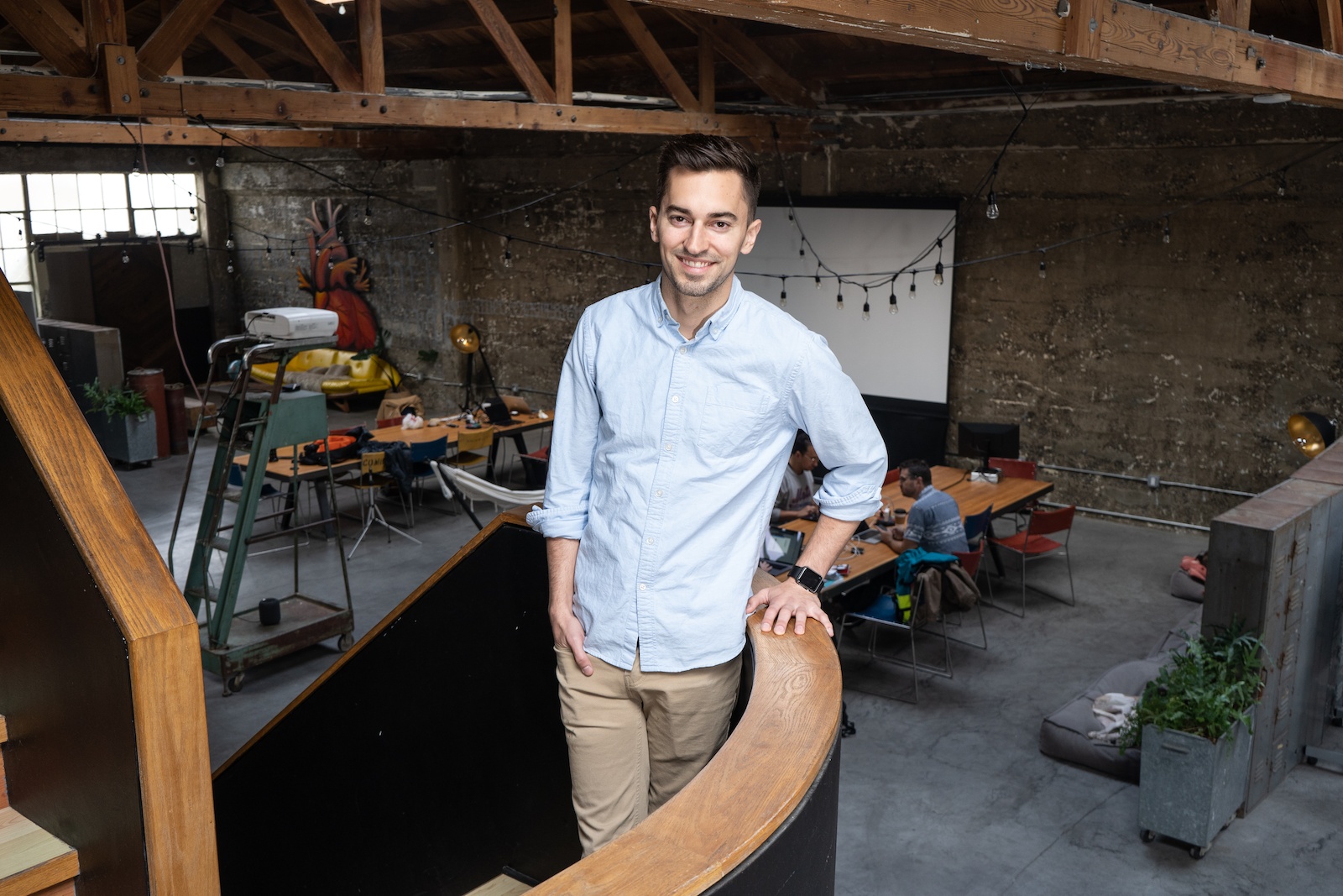 Cody Candee standing beside a wooden railing in a shared workspace