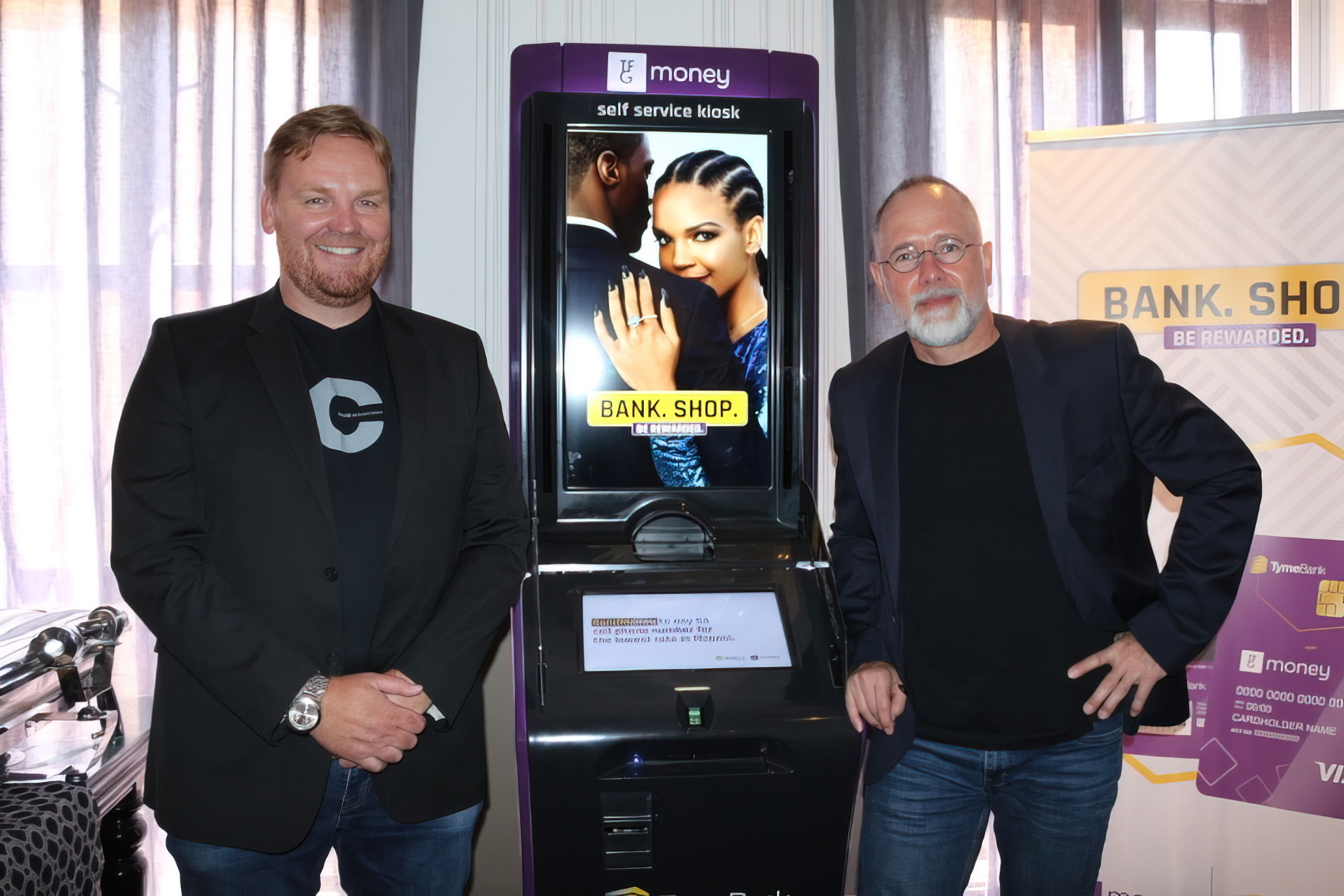 Coen Jonker, on the right, standing beside a TymeBank self-service kiosk with another attendee