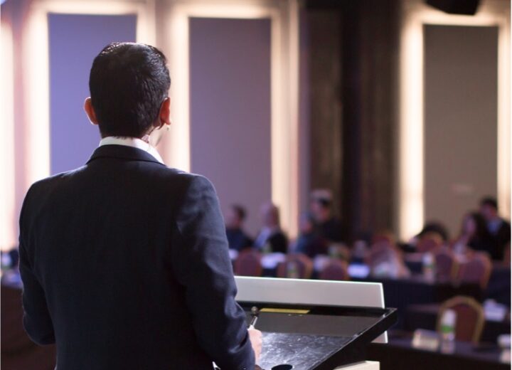 A speaker addresses a room from behind a lectern