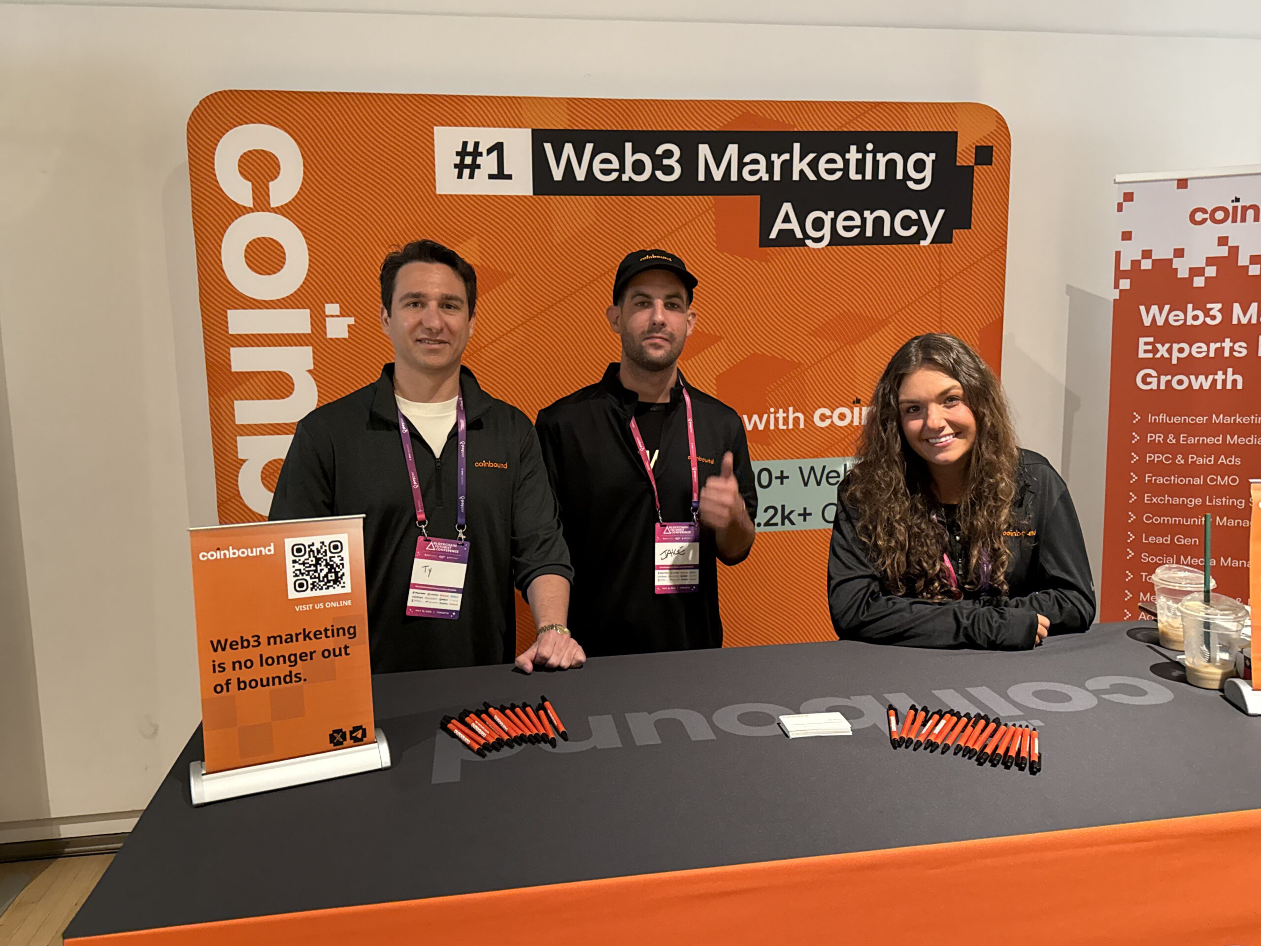 Three Coinbound team members at the company's orange conference booth