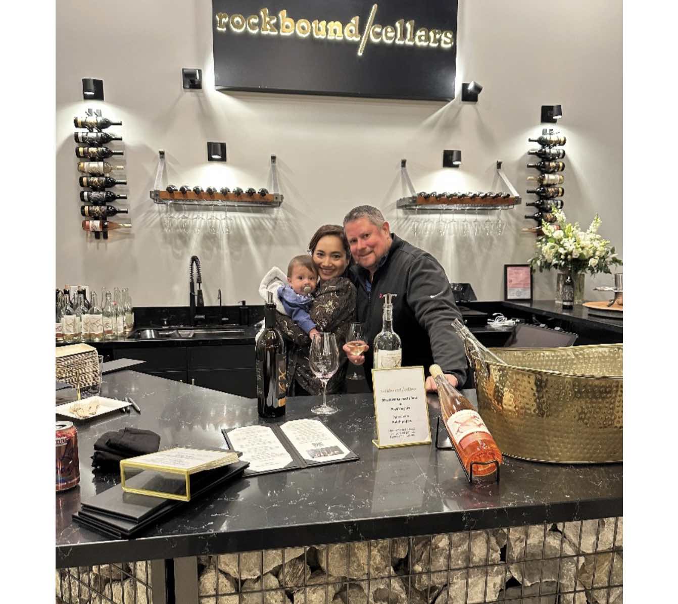 Fiorella and Colby DeRodeff with their son Felix behind the Rockbound Cellars tasting-room counter