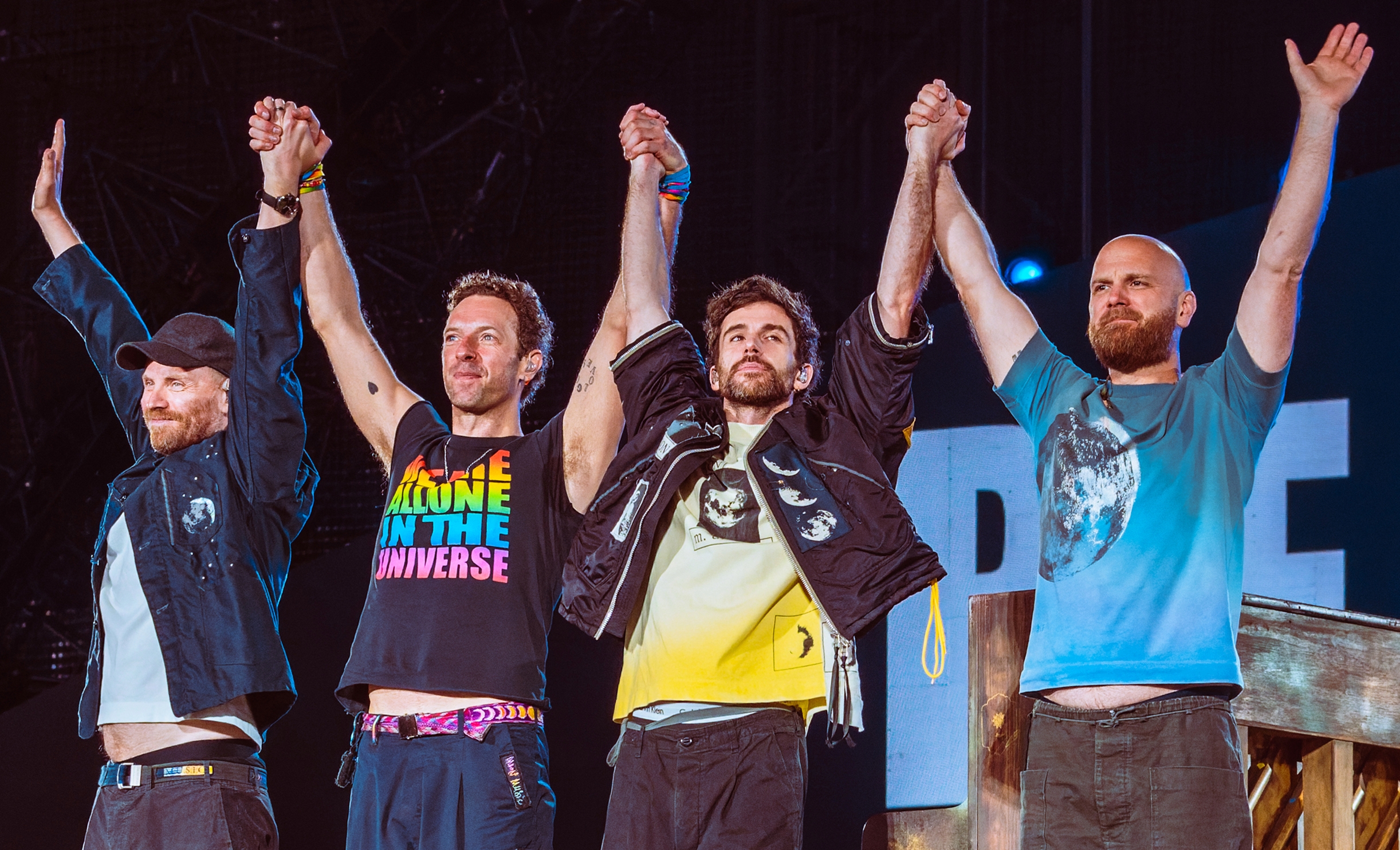 Coldplay's four performing members bow together on a brightly lit Wembley Stadium stage