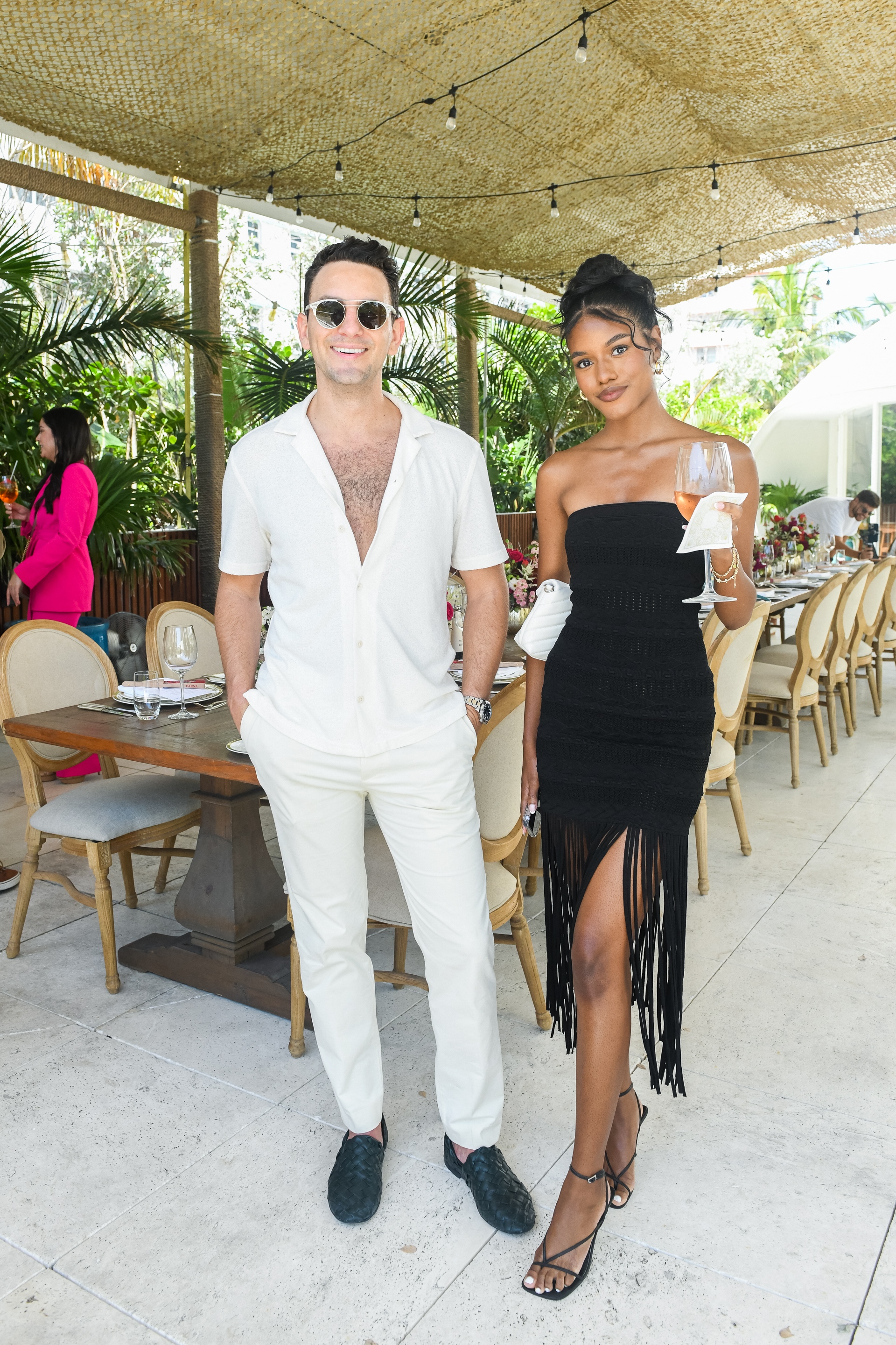 Cole Trider in a white shirt and trousers beside Shania Donaldson at the LOVED01 brunch in Miami Beach