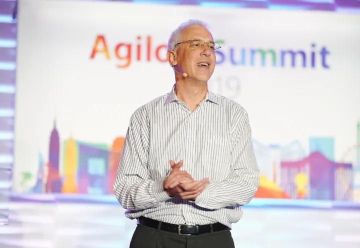 Colin Earl speaking onstage with a headset microphone at Agiloft Summit