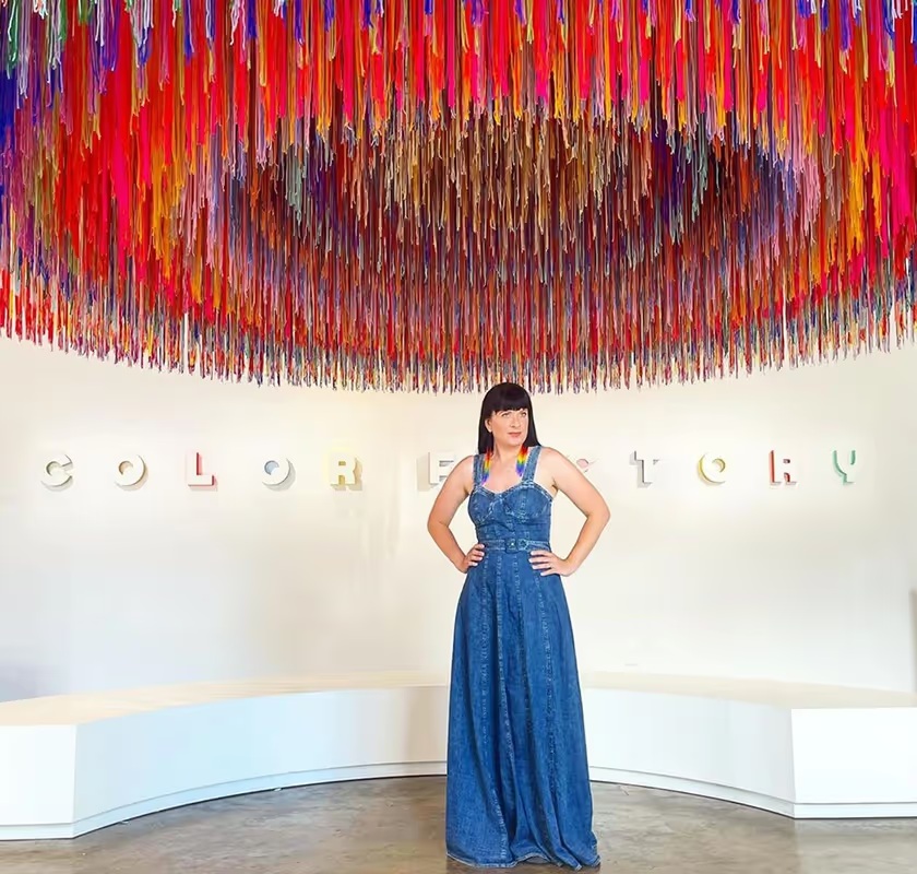 A visitor studying a circular installation made with multicolored yarn