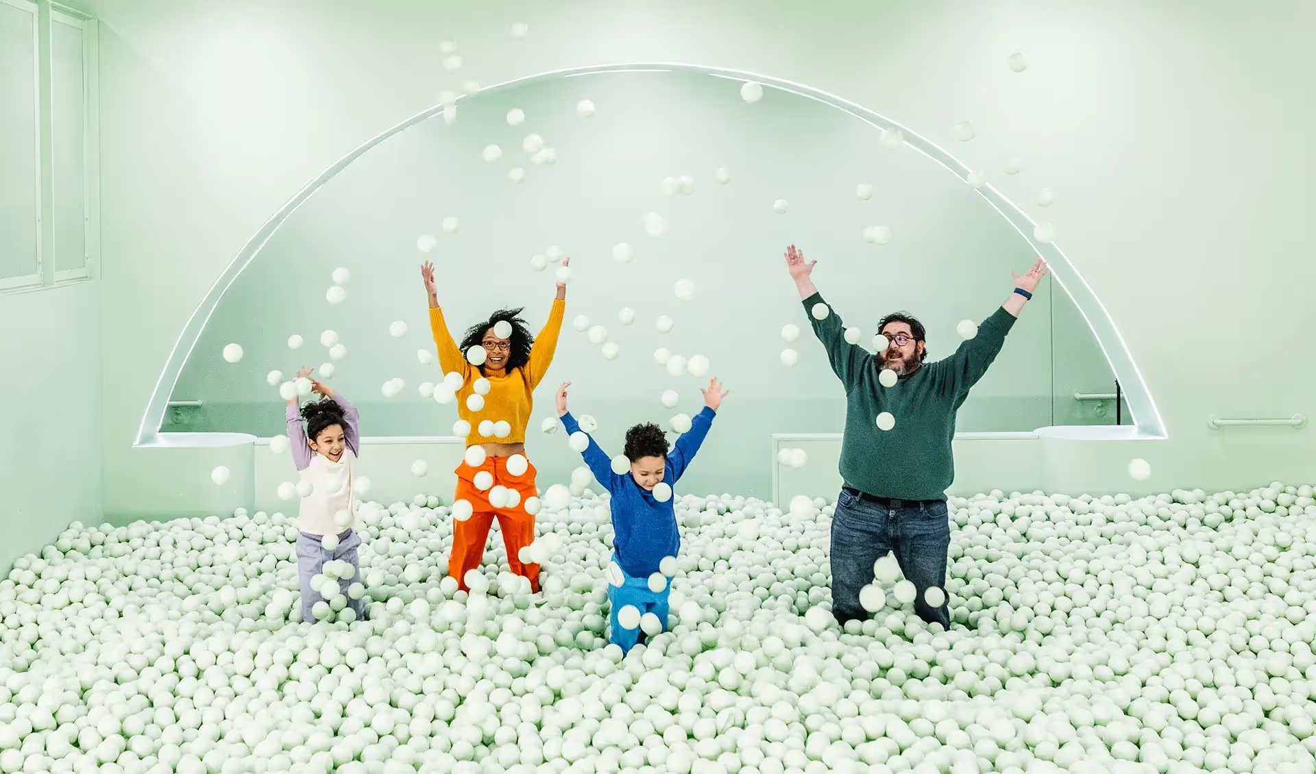 A family playing in Color Factory Chicago’s green ball pit
