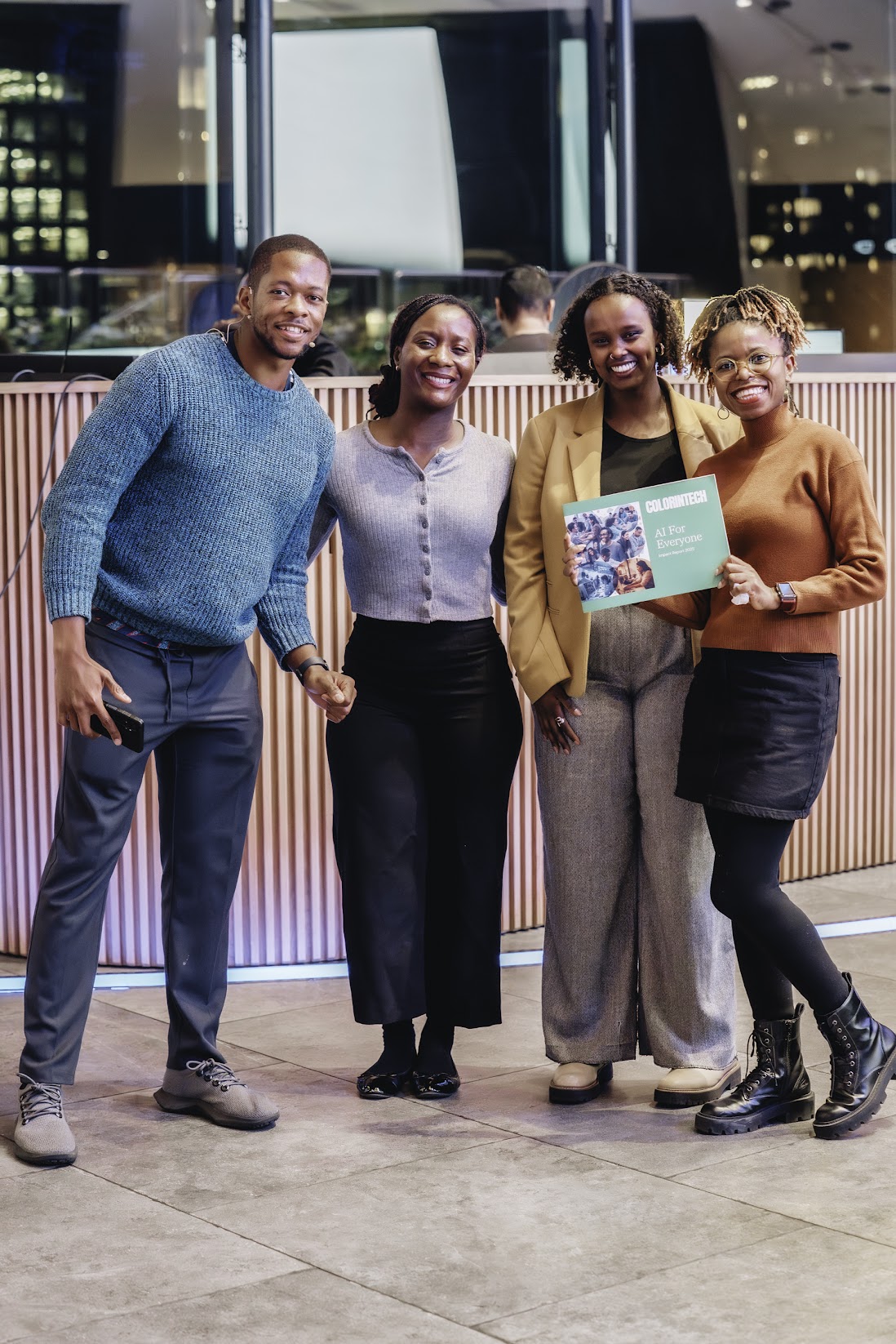 Four people standing together, holding Colorintech’s AI for Everyone Impact Report 2025