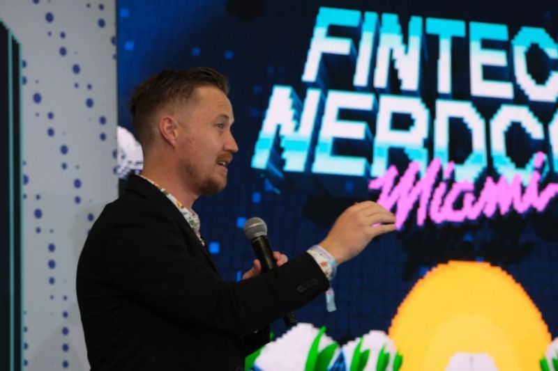 Colton Pond speaking with a microphone on the Fintech NerdCon Miami stage