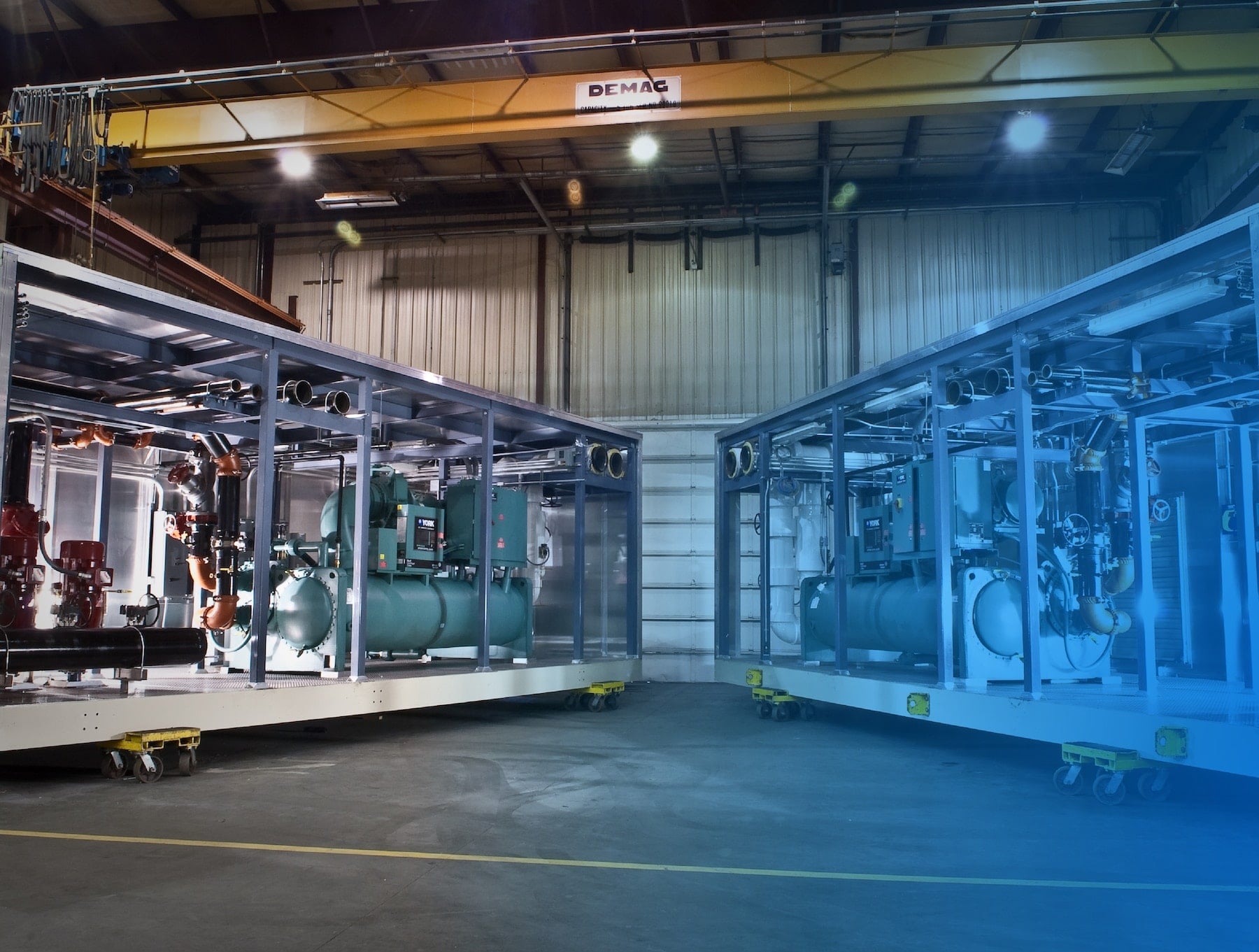 Large mechanical modules being assembled beneath a factory overhead crane