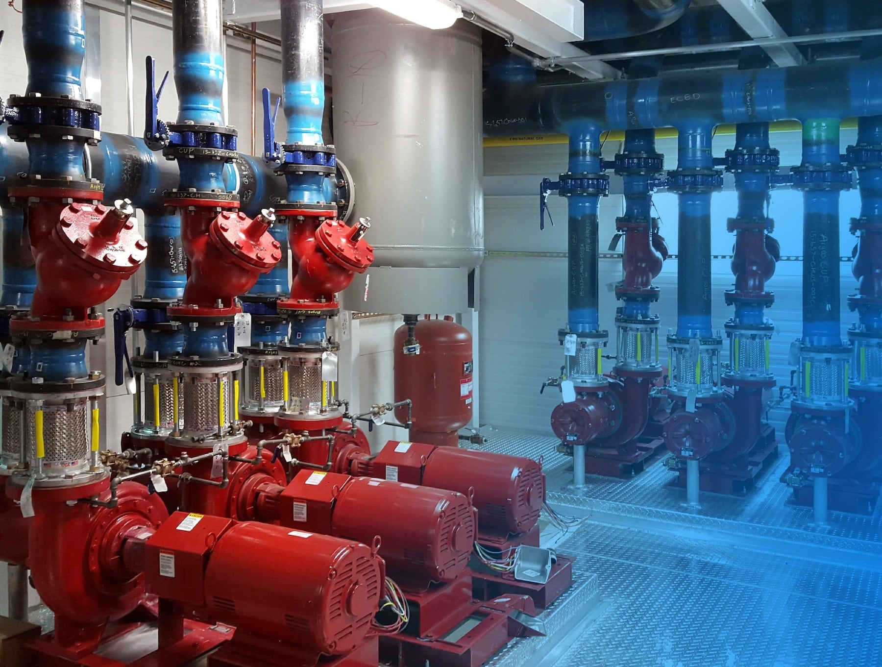 Red pumps and blue piping inside a mechanical plant