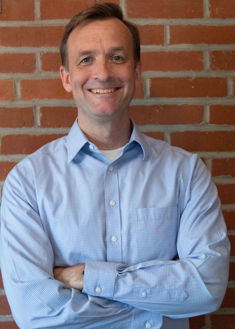 Communique CEO Adam Veile in front of a brick wall
