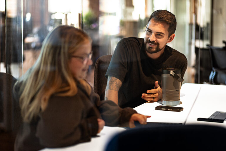 Two Community Agency team members in conversation at a meeting table