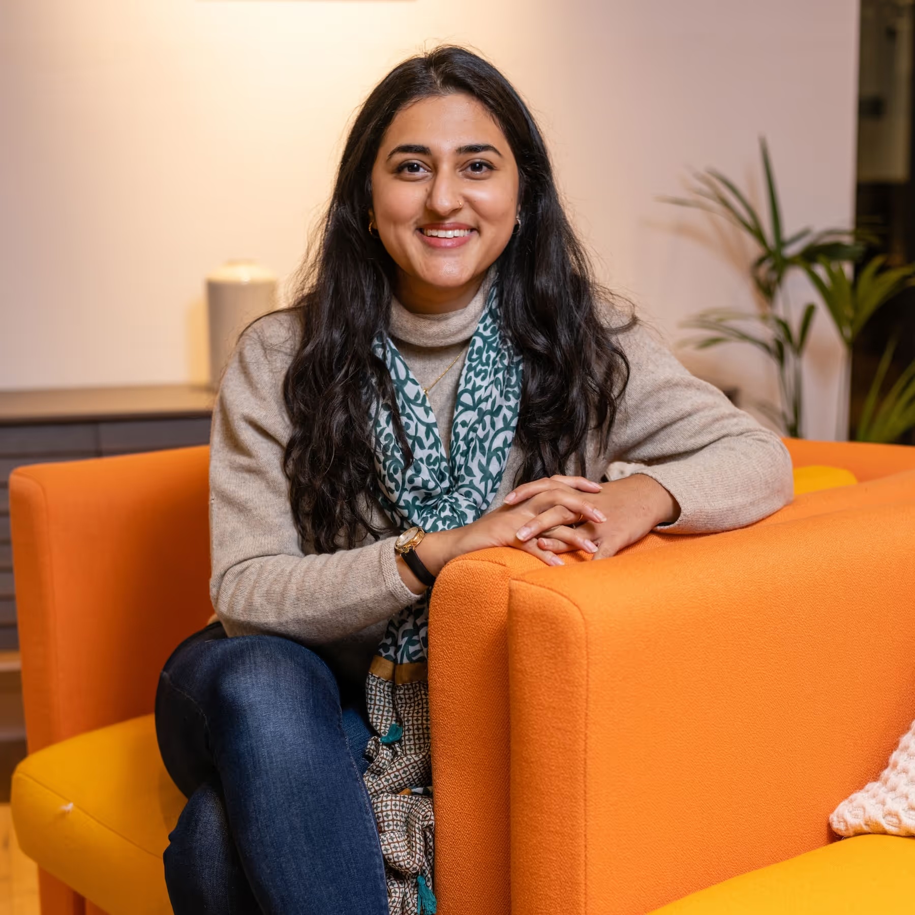Complyance founder and CEO Richa Kaul seated on an orange sofa