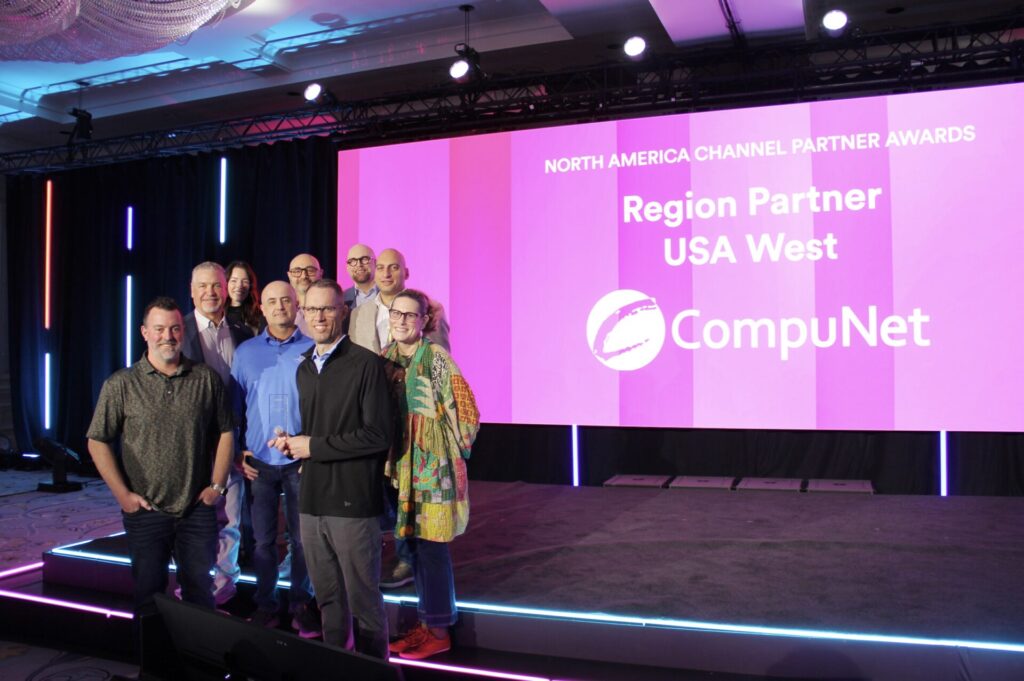 Group posing with a trophy in front of a screen recognizing CompuNet at Genetec’s North America Channel Partner Awards